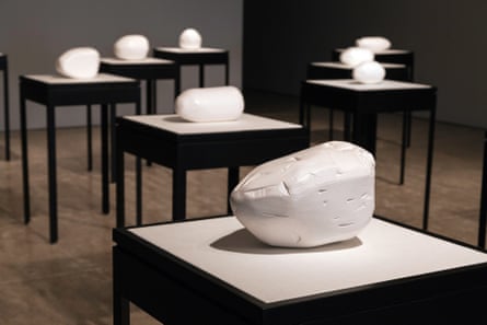 White, rock-like sculptures on rows of black and white pedestals.