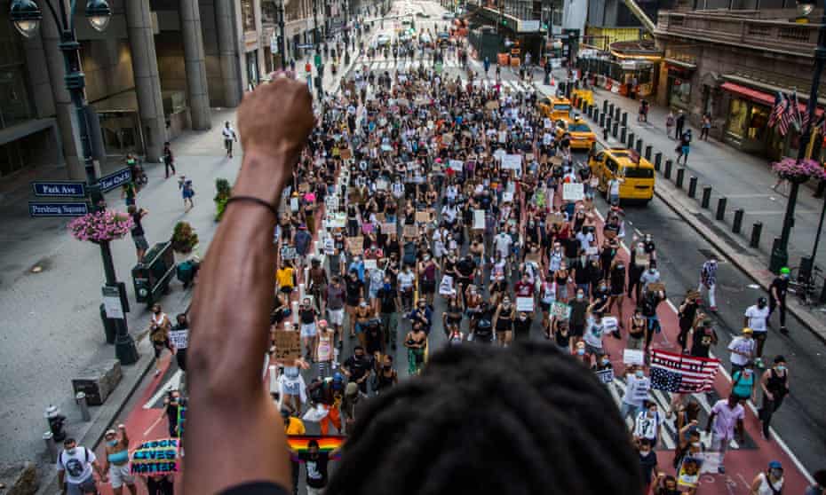 man raises arm in support as Black Lives Matter protesters walk in New York