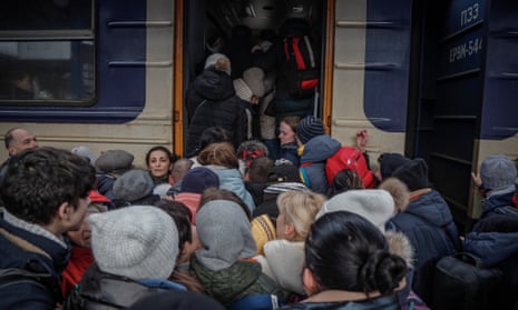 A crowd of people try to board a train