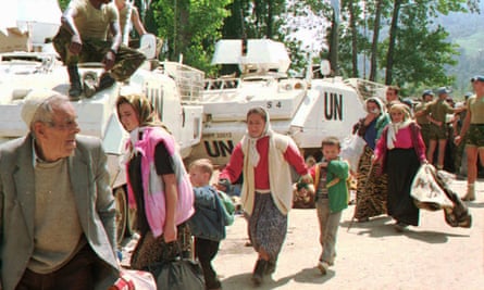 Muslim refugees from Srebrenica pass by UN armored personnel carriers, 13 July 1995.