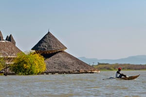 A fisherman paddles a traditional raft made from reeds past one of the submerged buildings of the Soi Lodge on the shores of Lake Baringo.