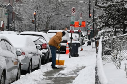 man shovels snow on sidewalk