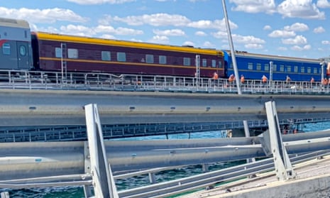In this still image from a video released on by the Russian National Antiterrorism Committee, a passenger train is seen passing by the damaged parts of an automobile link of the Crimean Bridge.