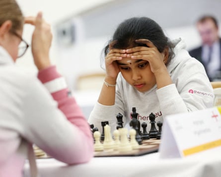 Bodhana Sivanandan deep in concentration with her head in her hands in front of a chessboard
