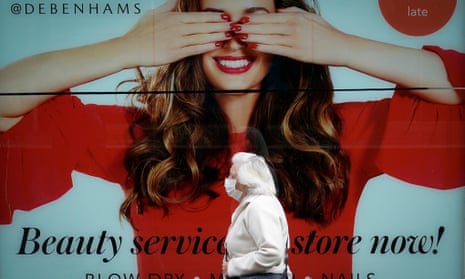 Elderly woman in mask walks past Debenhams shop front