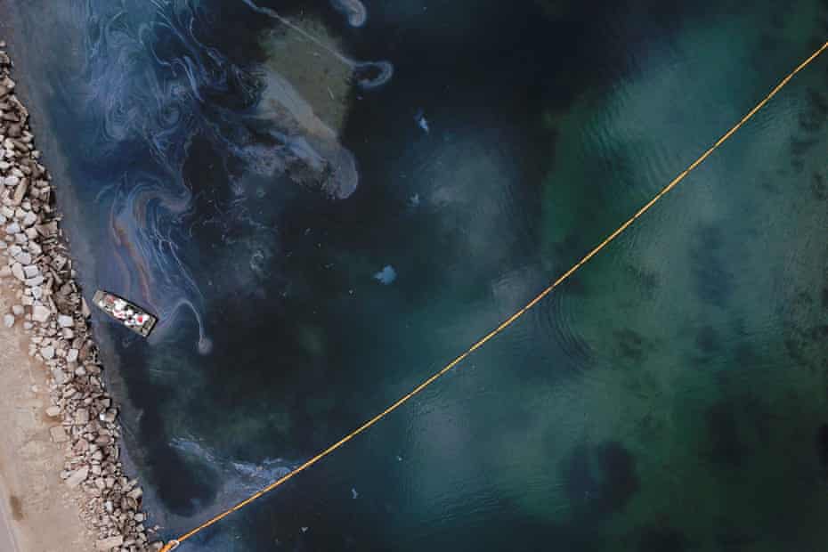 Environmental response crews clean up oil that flowed near the Talbert Marsh and Santa Ana River mouth, creating a sheen on the water.