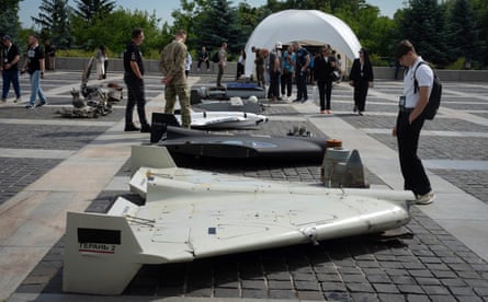 People stand looking at damaged drones arranged on the ground