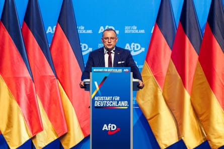 AfD’s co-leader Tino Chrupalla on stage surrounded by German flags makes a speech