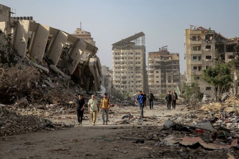 Palestinians walk amid rubble of destroyed buildings