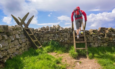 Hiker crossing a Stile - Hadrians Wall Walk.<br>A hiker crosses a stil on the Hadrian Walls Walk at Crag Lough in Northumberland, England, UK.