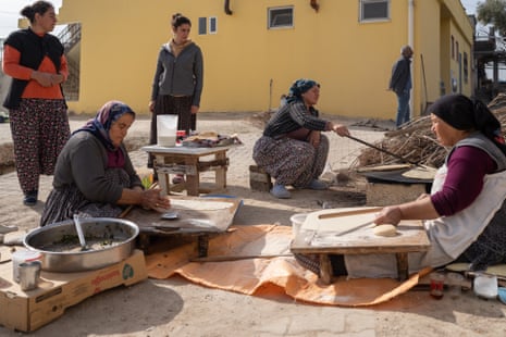 Women sitting outydoors preparing food in large metal pots