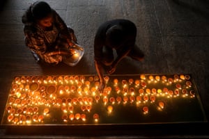 People lighting oil lamps in a dark temple room