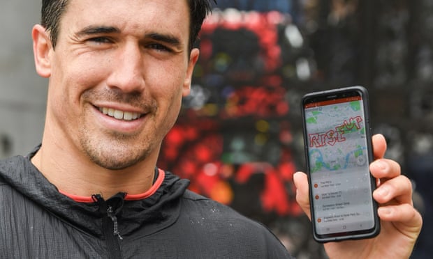 Reality TV star Joshua Patterson holding a phone showing a map of his unique 26.2 mile marathon route spelling out the words RISE UP on Strava.