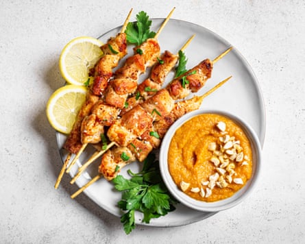 Grilled chicken pieces on wooden skewers with spicy peanut sauce