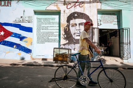 A man sells pastries in front of a mural of Che' Guevara