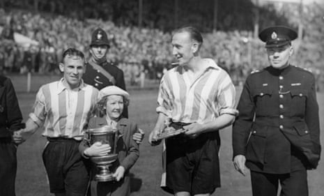 Brentford players Joe James and Idris Hopkins leave the pitch with James’ daughter Beryl after their 2-0 win over Portsmouth in the London War Cup in 1942.