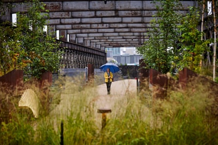 A woman with an umbrella walks through green space