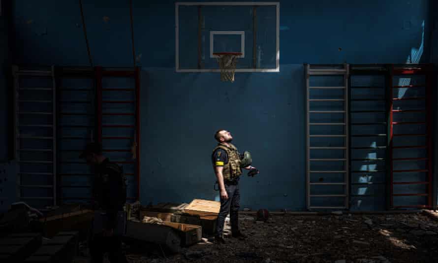 A Ukrainian policeman stands inside a school sport hall in the village of Vilkhivka, where, according to residents, Russian soldiers were based, after it was retaken by Ukrainian army.