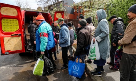 People wait in a line to collect humanitarian food aid after Russian shelling in Kherson.