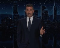 A man in a suit and tie speaks on a live television set