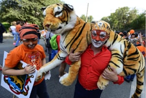 A man carrying a tiger plush toy takes part in a carnival parade marking Tiger Day