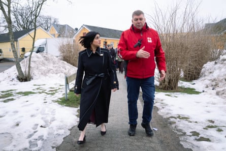 Shabana Mahmood walking along a snowy path with a man in a red jacket