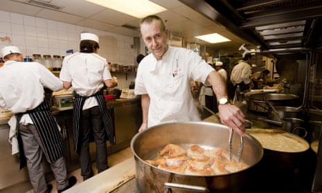 Michel Roux Jr in the kitchen of his restaurant Le Gavroche turning chicken legs in a saucepan using tongs