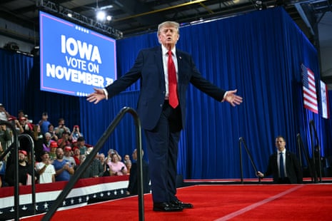 Donald Trump stands with his hands outstretched on a red carpet