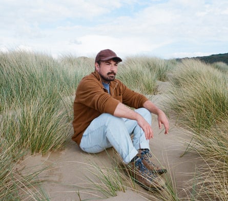Huw Marc Bennett sitting on a sand dune.