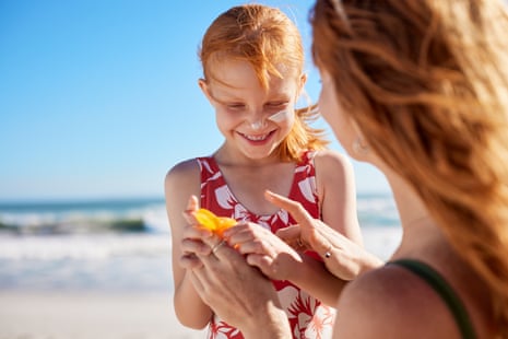 Mother applying sunscreen on little girl’s face