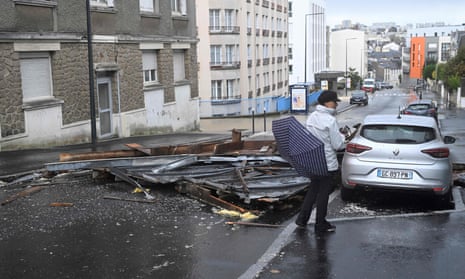 A pedestrian walks past the blown-off roof of a residential building (grey building, left) laying on the street in Brest, western France.