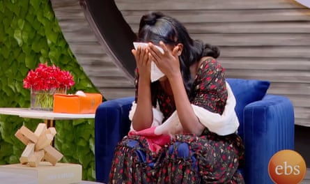 An African woman covers her face as she cries while sitting in a TV studio