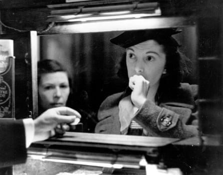 A woman buys a ticket at a theatre box office in 1939. A hand is coming out from the box office