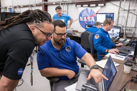 A Nasa team member points to a laptop as another looks on