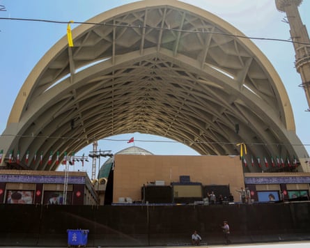 People at work on what could be a staging area beneath two arched roofs