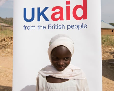 A Nigerian child stands in front of a sign that reads: 'UK aid from the British people'