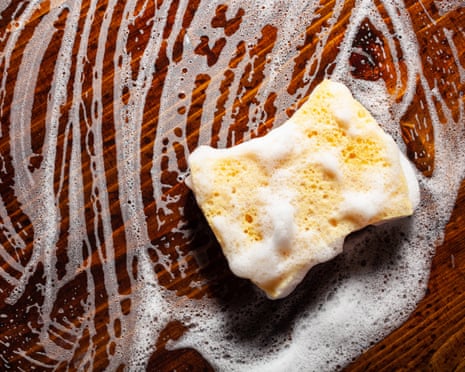 a wood cutting board being washed with a sponge