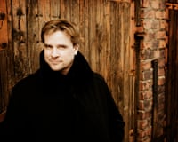Conductor John Storgards in a press publicity portrait against rustic backdrop.