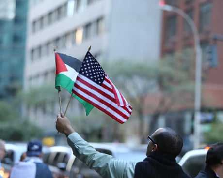 a man carrying US and Palestinian flags outside