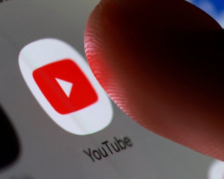 A thumb hovers over the YouTube app symbol on a smartphone