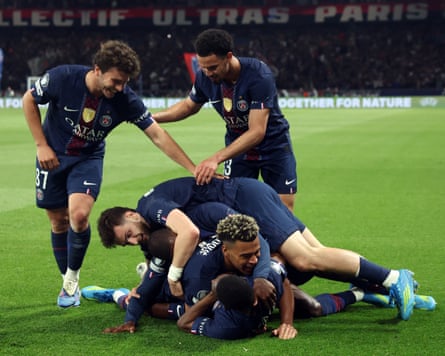 Paris Saint-Germain players Ousmane Dembélé (bottom), Désiré Doué (middle) and Khvicha Kvaratskhelia (top) celebrate a goal in a heap on the floor, with João Neves (left) and Warren Zaïre-Emery (right) standing either side of them, during their team's 5-4 Champions League semi-final first leg win at home to Bayern Munich.