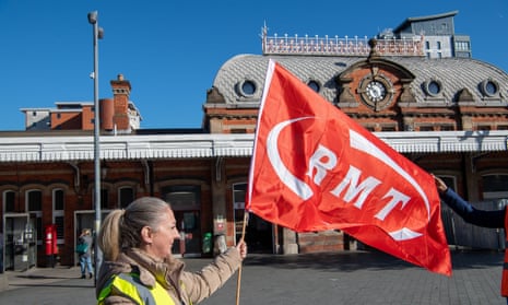 An RMT union member holds a flag outside Slough railway station in Berkshire on 8 October, when earlier strike action was taken. More strikes are planned for next week. 