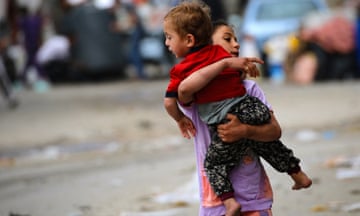 A Palestinian girl carries a toddler as people flee Rafah in the southern Gaza.