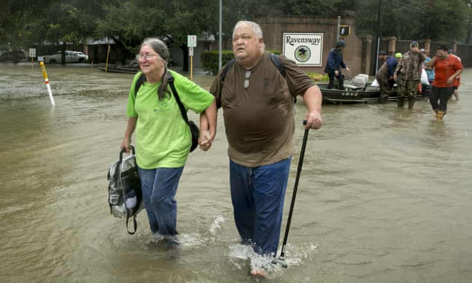 Margie David and her husband David Emswiler are rescued by volunteers on a boat from their flooded house in north-west Houston.