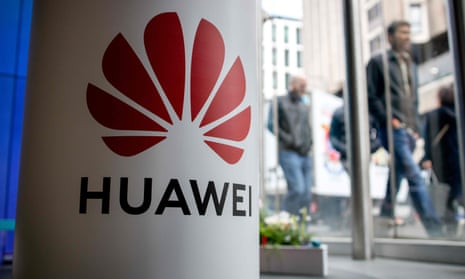 A pedestrian walks past a Huawei stand in central London