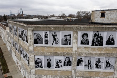 Seen from a nearby third story, a cement facade plastered with black-and-white portraits