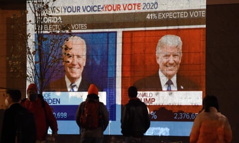 People watch a big screen displaying the live election results in Washington, DC on November 3, 2020.