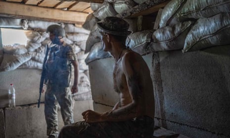 A Ukranian soldier watches his comrade at their position in a basement base, close to the frontline, in southern Ukraine on August 20, 2022, as the war enters its 178th day.