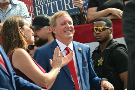 Ken Paxton smiles as a woman claps near him