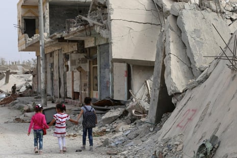 Syrian children walk past debris while heading to school on the second day of the new school year on 6 October 2015 in the Syrian Kurdish town of Kobane